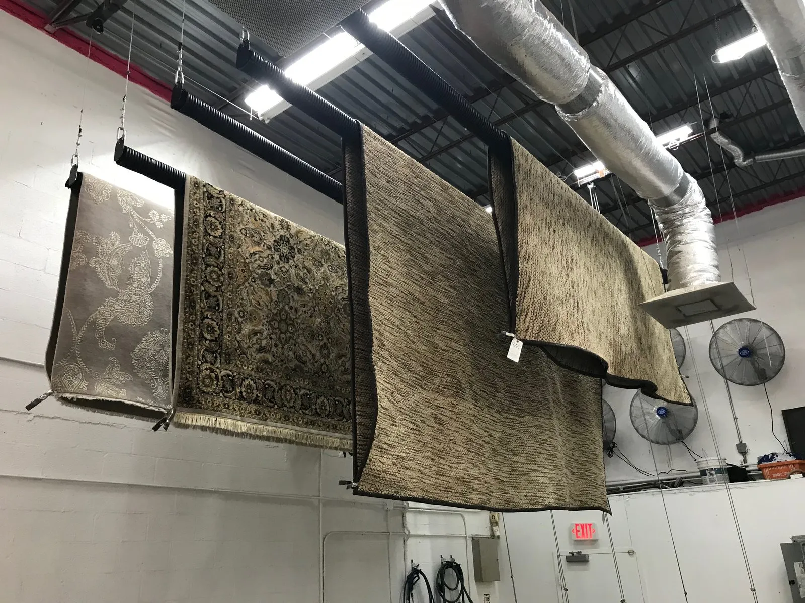 Washed rugs hung to dry from the ceiling of the controlled drying room