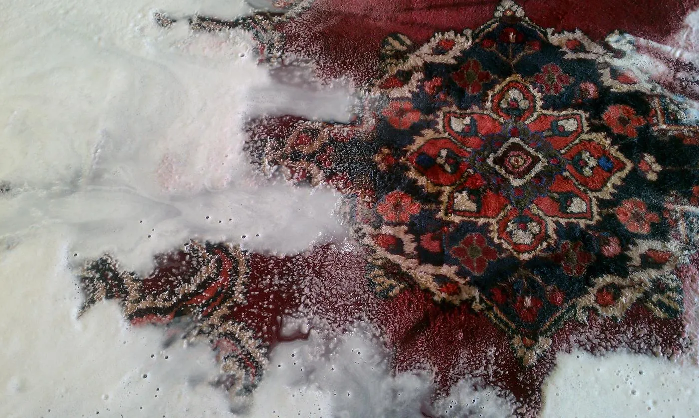 Hand-knotted rug covered in natural shampoo suds during a full wet wash