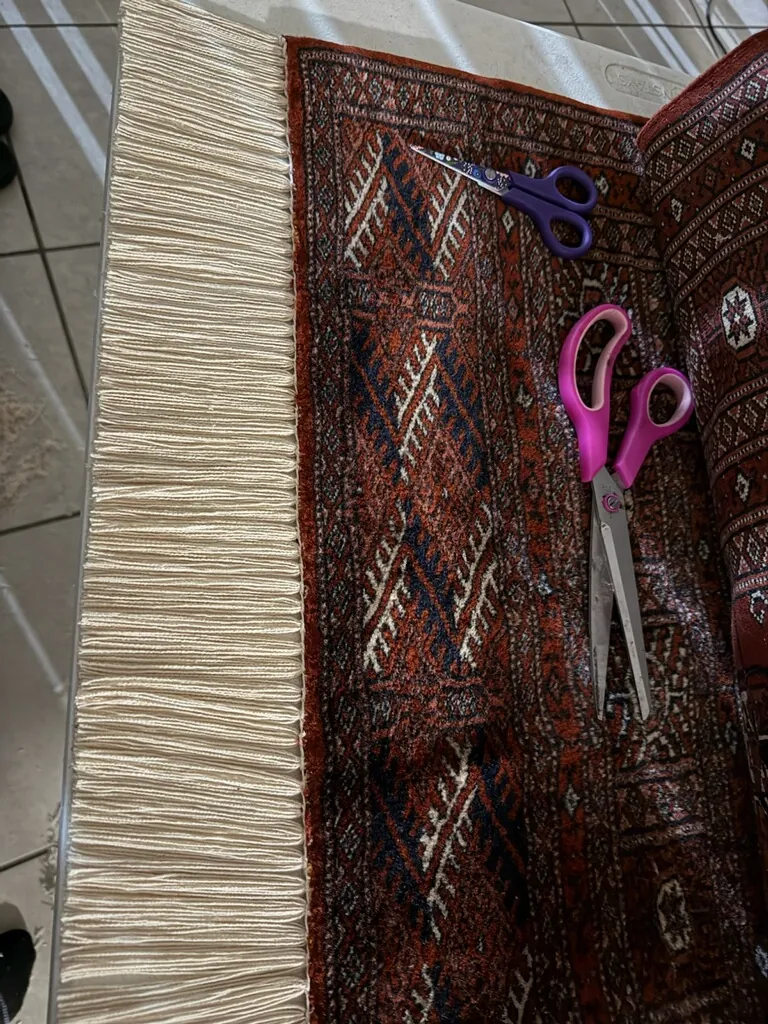 Scissors trimming yarn during hand repair of a colorful tribal rug